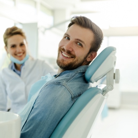 Man in denim shirt smiling in dental chair