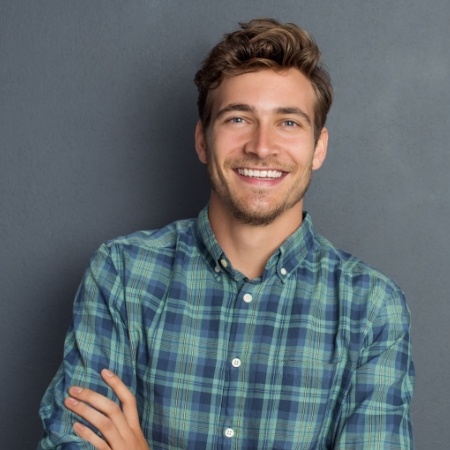 Man in green and blue plaid shirt grinning