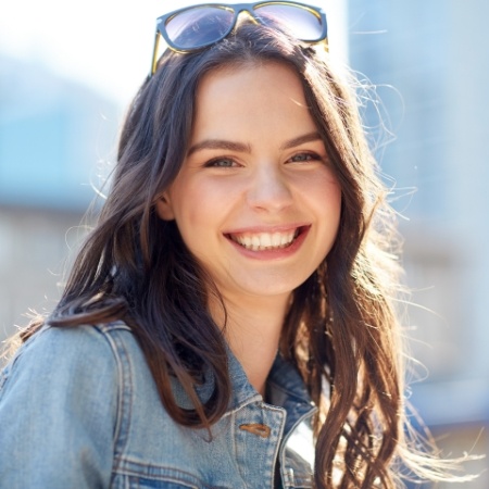 Young woman with sunglasses smiling outdoors