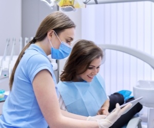 Dentist looking at a tablet with a patient