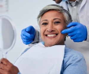 Dentist pointing to a woman grinning in dental chair