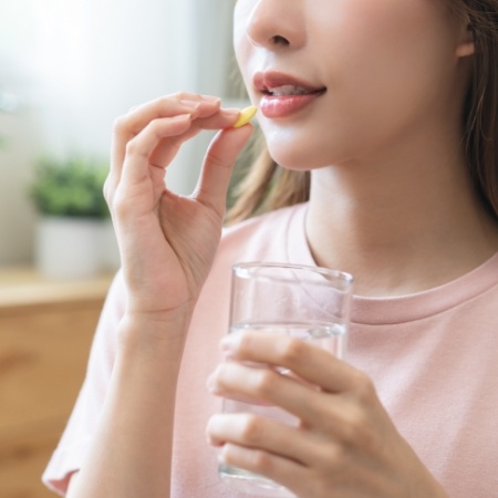 Woman taking pill with glass of water