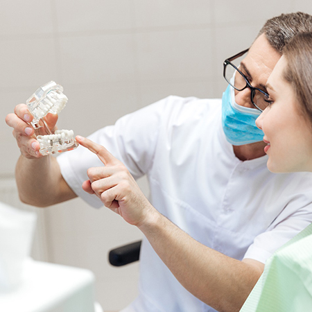 dentist using model to explain dental implants 