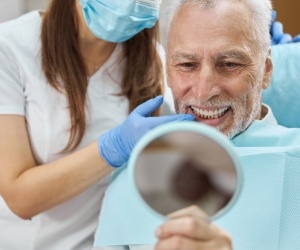 Senior dental patient admiring his smile in mirror