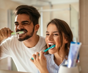 Man and woman brushing their teeth together