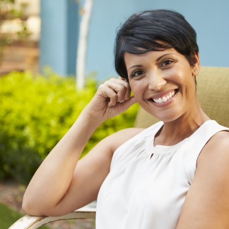 Woman in white blouse grinning outdoors