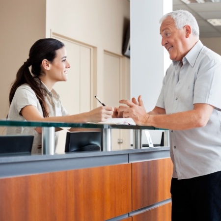 Senior man talking to dental receptionist