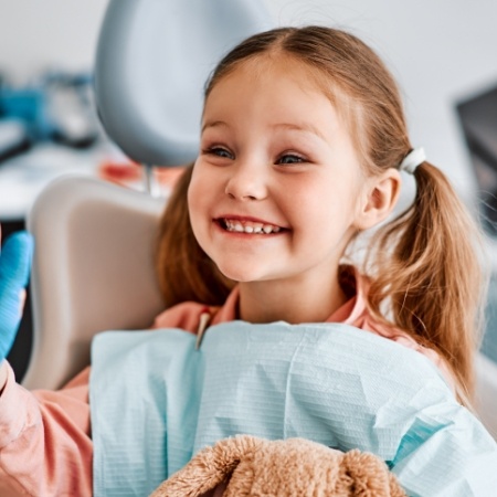 Young girl with pigtails grinning in dental chair