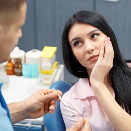 Dental patient holding her cheek in pain before root canal treatment in Falls Church