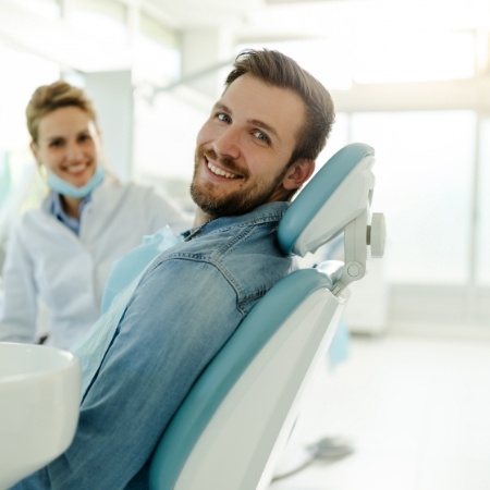 Man in denim shirt smiling in dental chair