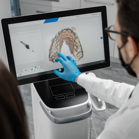 Dentist looking at digital models of a row of teeth on computer screen