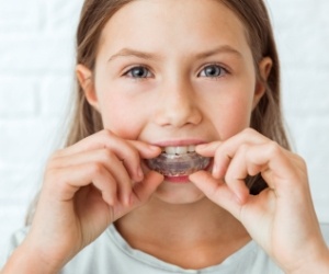 Young girl placing tray over her teeth