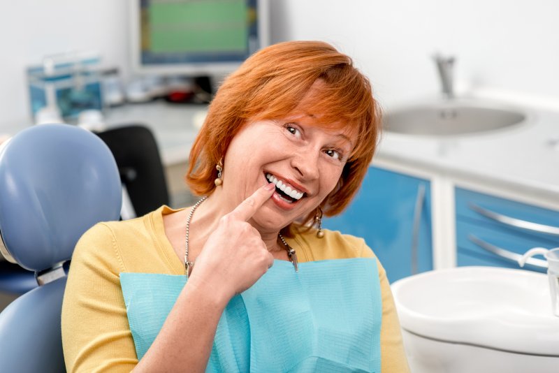 A senior woman pointing at her new dental implants