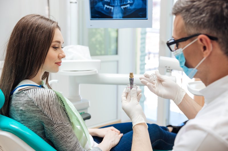 A dentist showing a patient how dental implants work