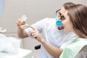 Dentist showing model dental implant to patient